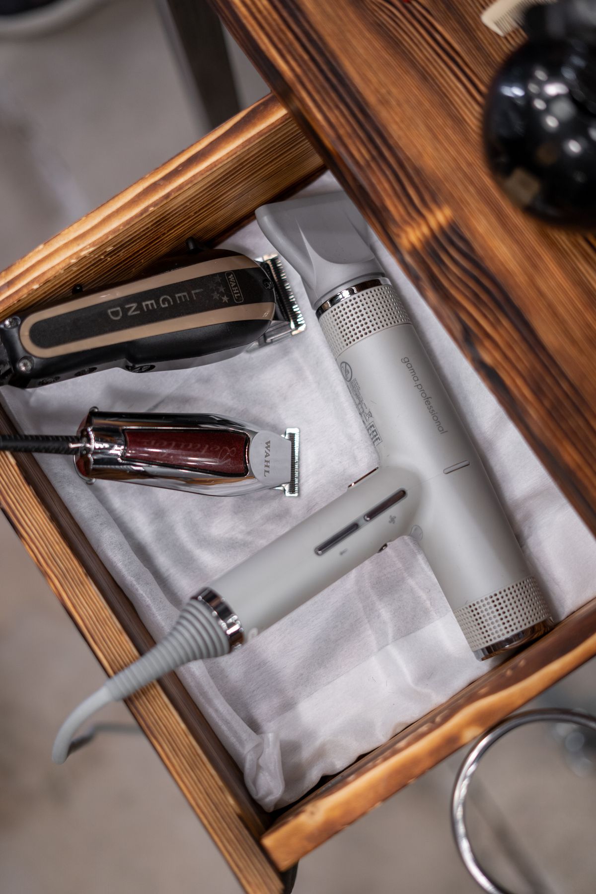Clippers and shears laid out in a wooden drawer at the shop